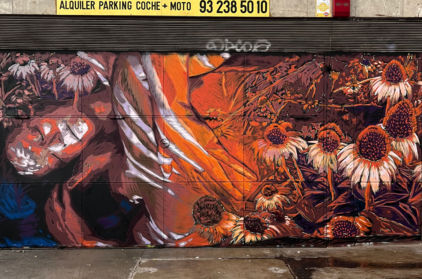 Fresque murale à Barcelone qui représente deux corps enlacés avec des fleurs autour dans des couleurs orange et bleu.