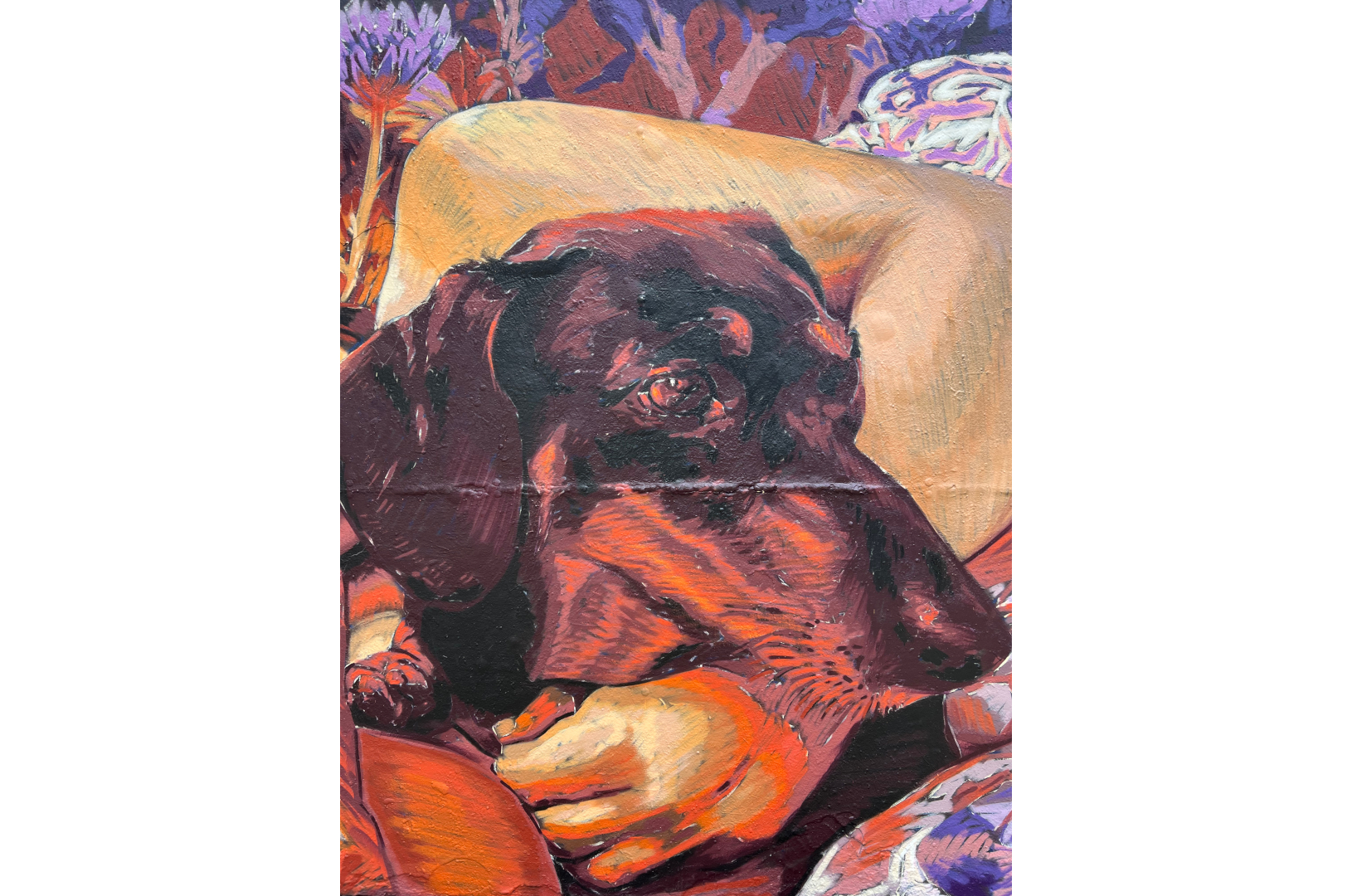 Fresque murale représentant une personne allongée, les yeux fermés, enlaçant un chien noir endormi. La scène, peinte dans des tons chauds de rouge, violet et orange, évoque la tendresse et l’intimité. L’œuvre est installée sur la place des Trois Cheminées (Tres Xemeneies) à Barcelone, dans un environnement urbain marqué par des structures industrielles et des arbres en arrière-plan.