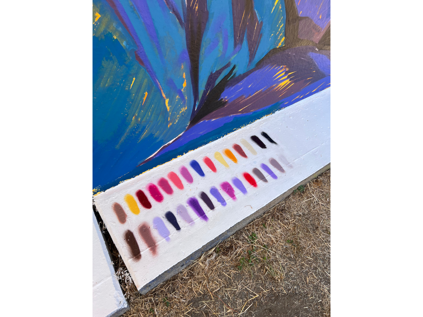 Fresque murale colorée représentant deux personnes allongées ou enlacées, peintes dans des tons vifs de bleu, rouge, orange et violet, installée en plein air dans le cadre du festival Plein Champ dans la ville du Mans.