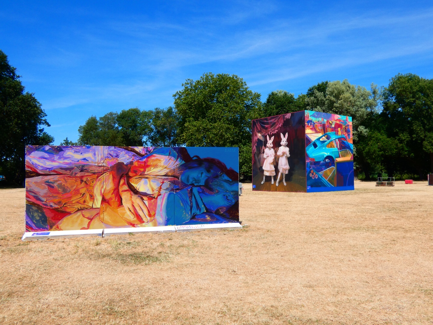 Fresque murale colorée représentant deux personnes allongées ou enlacées, peintes dans des tons vifs de bleu, rouge, orange et violet, installée en plein air dans le cadre du festival Plein Champ dans la ville du Mans.