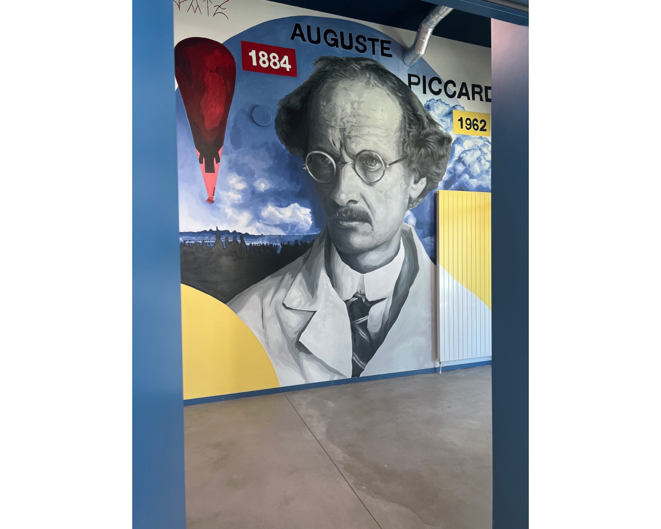 Fresque murale d’Auguste Piccard, pionnier de l’exploration de la stratosphère, entouré de son ballon, de nuages et de formes géométriques.